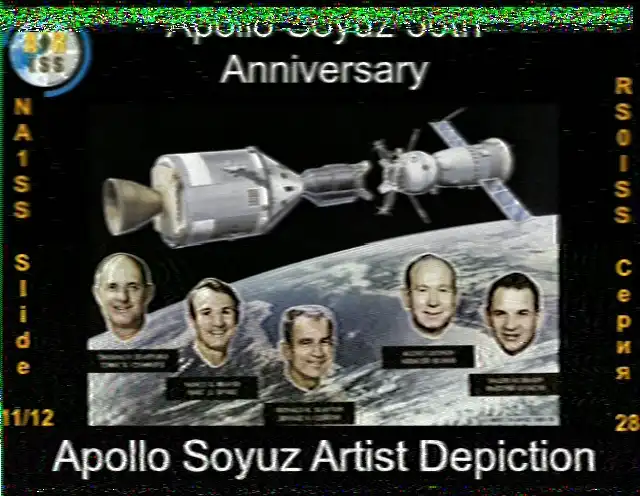 Obraz SSTV z ISS, slajd 11 z 12, z okazji 50. rocznicy misji Apollo-Sojuz. Obraz przedstawia artystyczną wizję statków kosmicznych Apollo i Sojuz zadokowanych razem na orbicie nad Ziemią. Poniżej statków kosmicznych znajdują się portrety pięciu członków załogi: astronautów Thomasa Stafforda, Vance'a Branda i Deke'a Slaytona oraz kosmonautów Aleksieja Leonowa i Walerija Kubasowa. Tekst na dole głosi 'Artystyczna wizja Apollo Sojuz'.